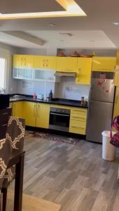 cocina con armarios amarillos y nevera de acero inoxidable en شقة مجهزة, en Tetuán