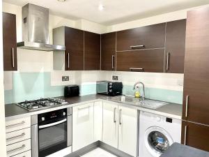 a kitchen with white cabinets and a washer and dryer at London 2Bedrooms 2Bathrooms, Balcony, Parking, Lovely South Woodford in London