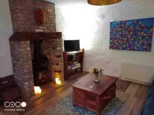 uma sala de estar com uma lareira de pedra e uma mesa em Traditional Irish Thatched Cottage em Florencecourt
