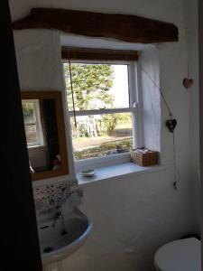 un bagno con lavandino e finestra di Traditional Irish Thatched Cottage a Florencecourt