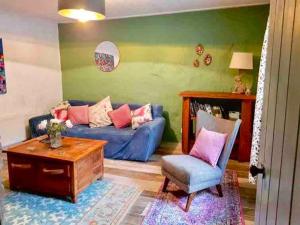 uma sala de estar com um sofá azul e uma cadeira em Traditional Irish Thatched Cottage em Florencecourt