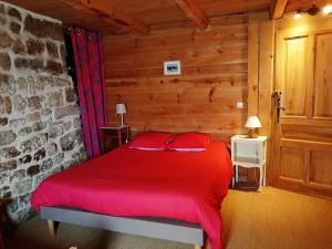 Una cama roja en una habitación con una pared de ladrillos. en Magnifique gite 14 personnes en bord de lac, en Devesset