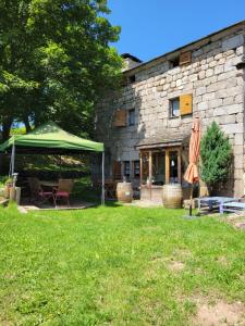 un patio con sombrilla verde, mesa y sillas en Magnifique gite 14 personnes en bord de lac, en Devesset 11 fotos más