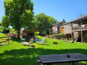 un patio con sillas y un banco de madera frente a un edificio en Magnifique gite 14 personnes en bord de lac, en Devesset