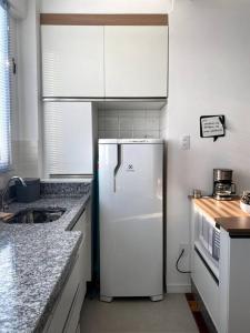 a kitchen with white cabinets and a white refrigerator at Apartamento com vista espetacular na Cidade Baixa in Porto Alegre