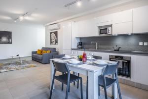 een keuken en een woonkamer met een witte tafel en stoelen bij Msida Park Residence C5 in Msida