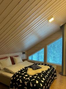 a bedroom with a bed and two windows at Villa LumiHelmi A & B in Äkäslompolo