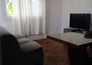 een woonkamer met een bank, een tafel en een televisie bij LA PERLA, departamento familiar in Mar del Plata