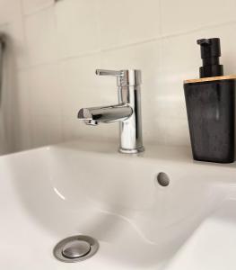 a white sink with a faucet and a cup at T2D Apartment - Suite UR proche Disneyland Paris in Bussy-Saint-Georges