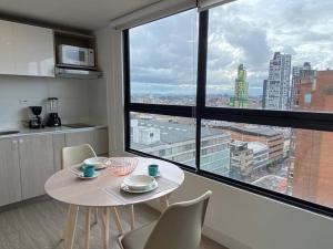 een tafel en stoelen in een kamer met een groot raam bij Apartamento academia 1201 in Bogota