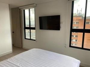 een slaapkamer met een bed en een flatscreen-tv aan de muur bij Apartamento academia 1201 in Bogota