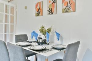 einen Esstisch mit Stühlen und einen weißen Tisch mit Tellern in der Unterkunft Lovely flat near University of Reading in Reading