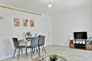 uma sala de estar com uma mesa e cadeiras e uma televisão em Lovely flat near University of Reading em Reading