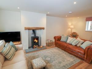 uma sala de estar com um sofá de couro e uma lareira em Cobble Cottage em Keswick
