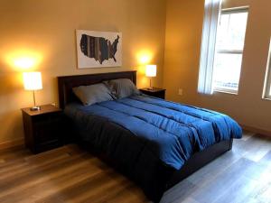 a bedroom with a bed with blue sheets and two lamps at Cannery Square Apartment 104 in Sun Prairie