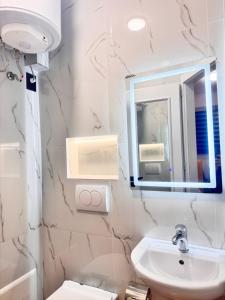 een witte badkamer met een wastafel en een spiegel bij Keli’s apartment in Tirana