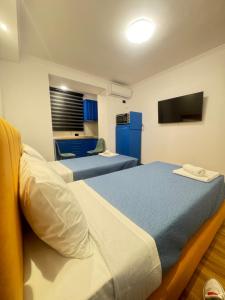 Keli’s apartment في تيرانا: سريرين في غرفة مع دواليب زرقاء وتلفزيون