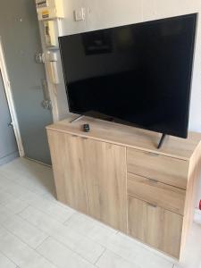 een flatscreen-tv bovenop een houten kast bij STUDIO LE HAVRE PLAGE in Le Havre