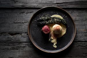 a black plate with food on a wooden table at Hotel-Restaurant-Café Krainer in Langenwang