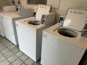una lavanderia con 3 lavatrici e un'asciugatrice di FairBridge Inn & Suites Richmond Hill a Richmond Hill