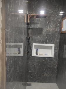 ein Bad mit einer Dusche und einer schwarzen Marmorwand in der Unterkunft Chalé Canastra Zoo in Capitólio