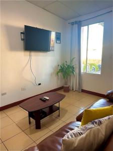 een woonkamer met een bank en een tv aan de muur bij Hidden Gem in Managua