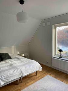 a white bedroom with a bed and a window at Hus precis intill sjö in Lindome