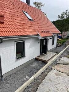 ein weißes Haus mit einem orangenen Dach und einer Veranda in der Unterkunft Hus precis intill sjö in Lindome
