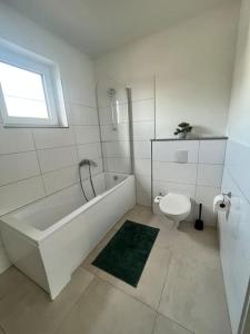 La salle de bains blanche est pourvue d'une baignoire et de toilettes. dans l'établissement 3 ZW 95 m2 Neubau Kostenlos Parkplatz im Hof, à Kitzingen
