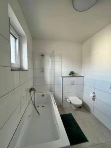 bagno bianco con vasca e servizi igienici di 3 ZW 95 m2 Neubau Kostenlos Parkplatz im Hof a Kitzingen