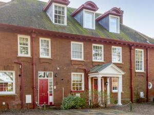 uma velha casa de tijolos com uma porta vermelha em Hampsire House em Cromer