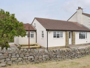 a white house with a stone wall in front of it at Rudda Farm Cottage - Uk2492 in Staintondale