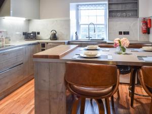 a kitchen with a large island with chairs and a table at Lochside Apartment in Inveraray