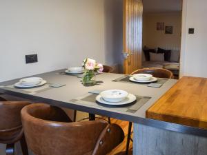 a table with plates and a vase of flowers on it at Lochside Apartment in Inveraray