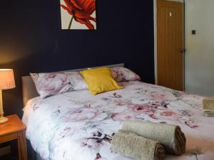 a bed with a flower blanket and a yellow pillow at Lochside Apartment in Inveraray