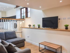 a living room with a couch and a flat screen tv at Tarn Cottage - Uk42803 in Mungrisdale