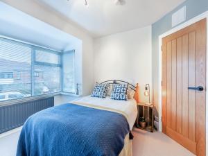 a bedroom with a bed with a blue blanket and a window at 25 Appledore Gardens in Chester-le-Street