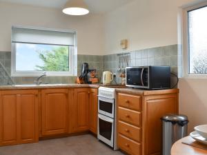 a kitchen with wooden cabinets and a microwave and a window at Crosslands in Penrith