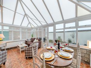 a conservatory dining room with a table and chairs at The Roddy House in West Bay