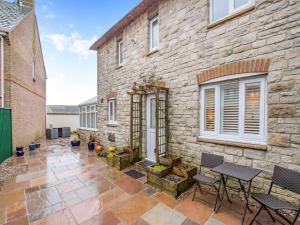 a stone house with a patio with chairs and a table at The Roddy House in West Bay