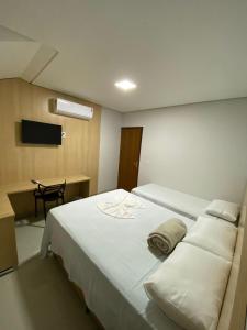 1 dormitorio con 1 cama blanca grande y escritorio en Hotel dos viajantes, en Sorriso