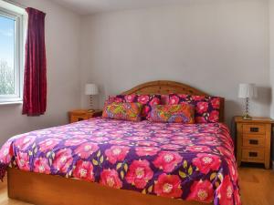 um quarto com uma cama com um edredão colorido em The Stables em Ely
