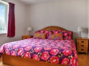 a bedroom with a bed with a colorful comforter at The Stables in Ely