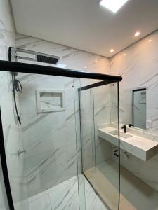 a bathroom with a glass shower and a sink at Hotel dos viajantes in Sorriso