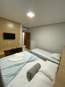 Habitación de hotel con 2 camas y TV de pantalla plana. en Hotel dos viajantes, en Sorriso