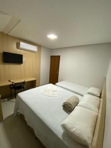 1 dormitorio con 1 cama con sábanas y almohadas blancas en Hotel dos viajantes, en Sorriso