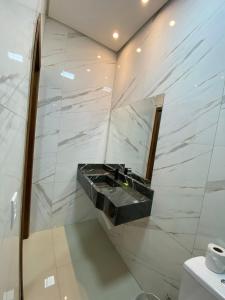 a bathroom with a black sink and marble walls at Hotel dos viajantes in Sorriso