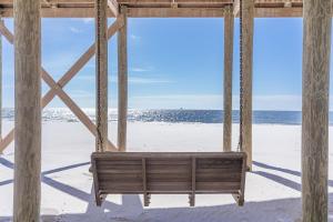 a swing on the beach with the ocean behind it at Waves of Grace in Dauphin Island