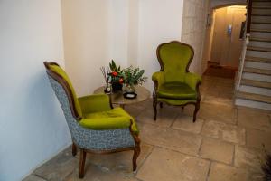 2 grüne Stühle und ein Tisch in einem Zimmer in der Unterkunft CASA ALMIKA PRINCIPE AMEDEO in Bari