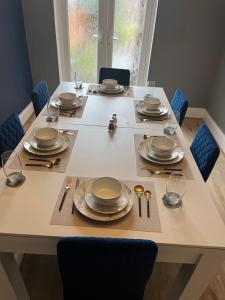 einen Tisch mit Tellern und Besteck darüber in der Unterkunft Spacious 5 Bed Home in Birmingham Perfect for Families and Contractors! in Birmingham